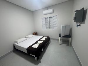 a white bedroom with a bed and a chair at Pousada In'capitólio in Capitólio