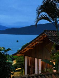 a house with a palm tree next to the water at Janaína Picinguaba in Ubatuba