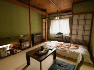 a room with a bed and a coffee table in it at Sakaenoyu Ryokan in Matsumoto +76 photos