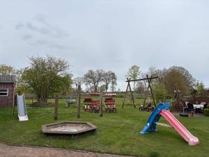 a park with a playground with a slide and swings at Ferienhaus Franzen 35679 in Uplengen