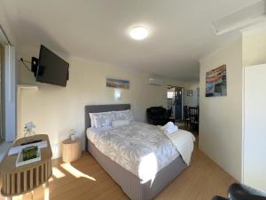 a bedroom with a bed and a flat screen tv at Cosy Bayside Studio in Esperance