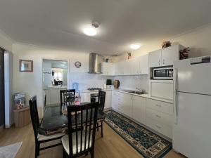 a kitchen with a table and chairs and a refrigerator at Cosy Bayside Studio in Esperance +6 photos
