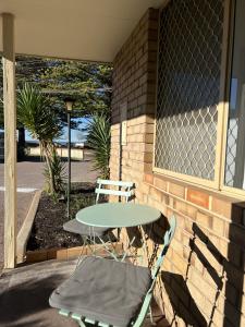 a table and chairs sitting next to a brick wall at Cosy Bayside Studio in Esperance