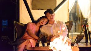 a man and a woman sitting in front of a fire at Gapyeong Gratia glamping in Gapyeong