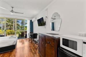 a room with a bed and a kitchen with a microwave at Motel Miramar in Nambucca Heads