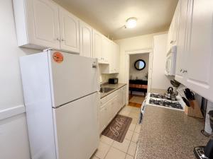 a kitchen with white cabinets and a white refrigerator at Sun-filled Unit, Elevator, Pool, Boston College in Boston +9 photos