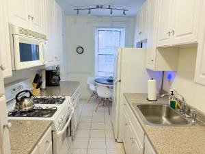 a kitchen with white cabinets and a sink and a stove at Sun-filled Unit, Elevator, Pool, Boston College in Boston