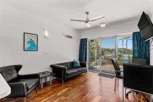 a living room with black leather furniture and a balcony at Motel Miramar in Nambucca Heads