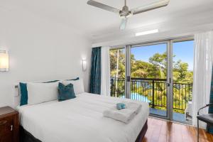 a bedroom with a large white bed with a balcony at Motel Miramar in Nambucca Heads +152 photos