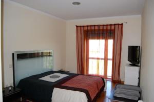 a bedroom with a bed and a television and a window at H2OPorto Beachfront Apartment in Vila Nova de Gaia