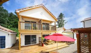 a house with a balcony and a red umbrella at Samcheok lime pension in Samcheok