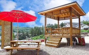 a gazebo with a bench and a red umbrella at Samcheok lime pension in Samcheok