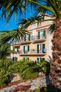 un edificio con persianas verdes y una palmera en Villa Dei Sogni, en Katelios
