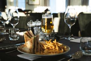 a plate of food and french fries on a table with wine glasses at Hotel Grimsborgir by Keahotels in Ásborgir +64 photos