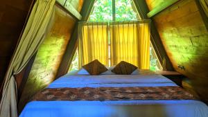 a bed in a room with a large window at Balkondes Saka Pitu in Kembanglimus