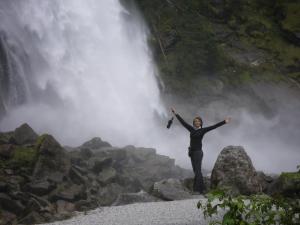 una mujer parada en las rocas frente a una cascada en Pension Heilbad Burgwies, en Stuhlfelden