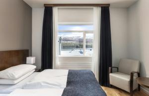 a bedroom with a bed and a window and a chair at Hotel Kea by Keahotels in Akureyri +97 photos