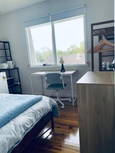 a bedroom with a bed and a desk and a window at Coral House in Sydney