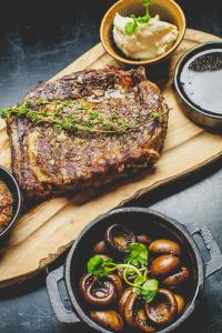 a steak on a cutting board with a plate of food at Hotel Kea by Keahotels in Akureyri
