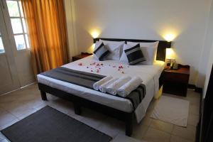 a bedroom with a bed with red rose petals on it at Nathaliya Tourist Hotel in Seeduwa