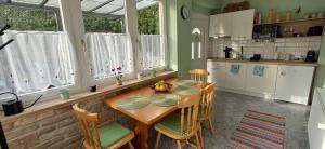 a kitchen with a wooden table and some windows at Igali Varázs Apartman 2 perc a fürdőtől in Igal