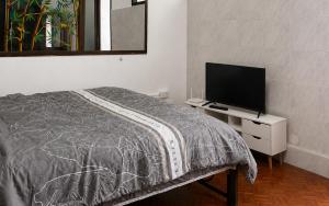 ein Schlafzimmer mit einem Bett und einem Fernseher auf einer Kommode in der Unterkunft ST Apartment in Dusit