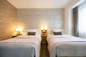a hotel room with two beds and a window at JR-East Hotel Mets Kitakami in Kitakami