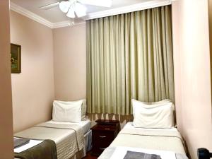 a hotel room with two beds and a window at Apartamento Uberlândia - BH in Belo Horizonte
