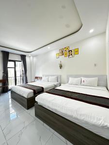two beds in a room with white walls at RUBY HOTEL in Tây Ninh