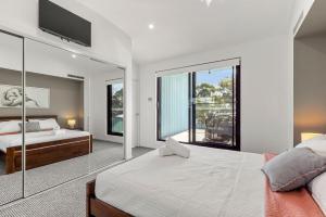 a bedroom with two beds and a large window at Bruma on Bowen - Opposite Shark Net Beach in Huskisson