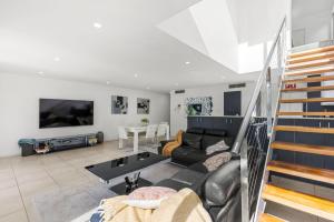 a living room with a couch and a tv at Bruma on Bowen - Opposite Shark Net Beach in Huskisson