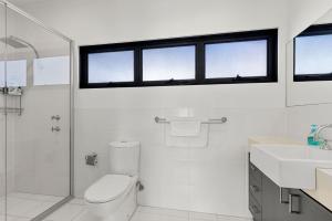 a white bathroom with a toilet and a sink at Bruma on Bowen - Opposite Shark Net Beach in Huskisson +41 photos