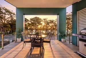 a patio with a table and chairs on a deck at Bruma on Bowen - Opposite Shark Net Beach in Huskisson