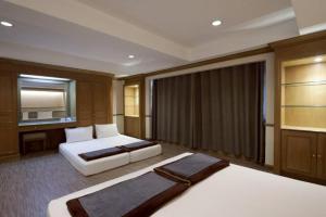 a hotel room with two beds and a television at Alameda Suites Hotel in Bangkok