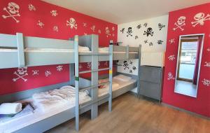 a room with three bunk beds with a red wall at Alpking Hostel in Ellmau