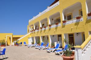 une rangée de chaises devant un bâtiment jaune dans l'établissement Hotel Mare Blu, à Lampedusa