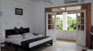 a bedroom with a bed and a large window at Nathaliya Tourist Hotel in Seeduwa