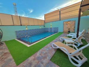 a swimming pool with lounge chairs and a swimming pool at La Gabbia Chalets in Al Kafrayn
