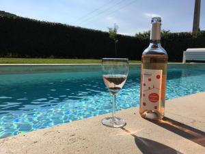 una bottiglia di vino e un bicchiere accanto alla piscina di Villa Le Grimpeur Malaucène a Malaucène