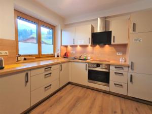 a large kitchen with white cabinets and a window at Alpking Hostel in Ellmau