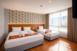 ein Hotelzimmer mit zwei Betten und einem Fenster in der Unterkunft CBD Hotel Suratthani in Surat Thani + 64 Fotos