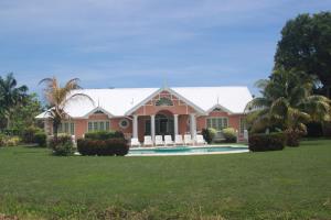 a pink house with a pool and palm trees at Villa Sans-Souci in Lowlands