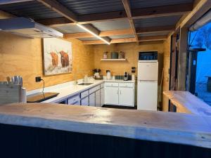 a large kitchen with white cabinets and a refrigerator at Forest Hillside Glamping Retreat in Lochiel