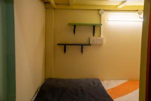 a room with a bed and a green shelf on the wall at Bestow Capsule Hostel in Kuala Lumpur