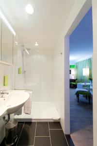 een witte badkamer met een wastafel en een douche bij Bonnox Boardinghouse & Hotel in Bonn