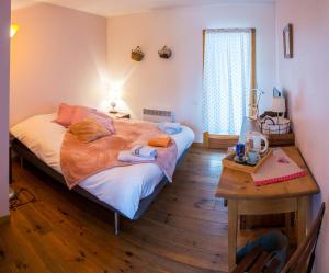 a bedroom with a large bed and a table at Les Chambres de la Weiss in Kaysersberg