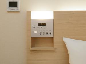 a thermostat on a wall next to a pillow at Keio Presso Inn Gotanda in Tokyo