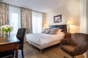 a hotel room with a bed and a desk and a chair at Waldorf Montparnasse in Paris