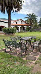 two benches sitting next to a table in a park at La mansión in Salta