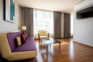 ein Wohnzimmer mit einem lila Sofa und einem Tisch in der Unterkunft CBD Hotel Suratthani in Surat Thani